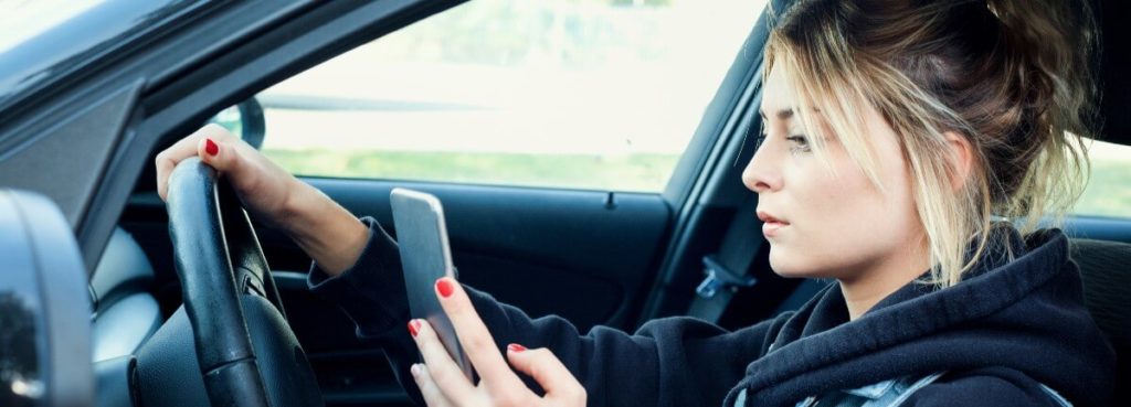 young woman on phone behind wheel
