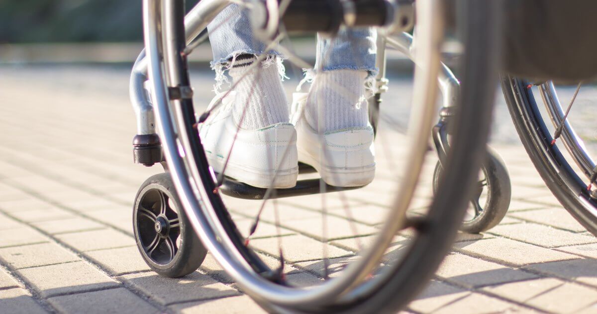 close-up image of back wheel of a wheelchair on brick road